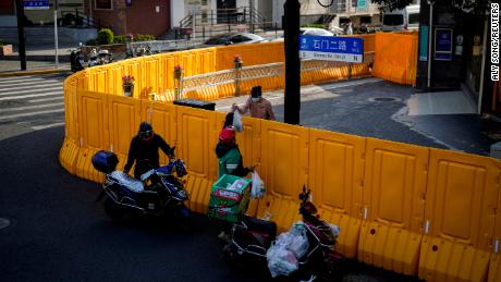 A delivery worker passes food to a woman over the barriers of a closed area in Shanghai on March 23, 2022. 