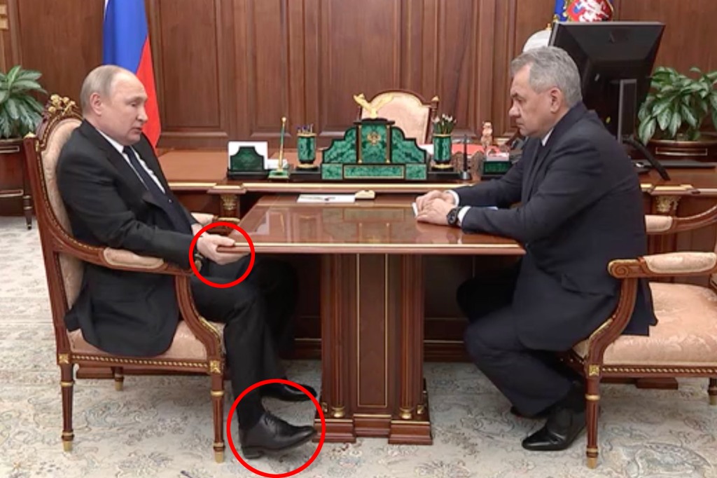 Vladimir Putin is seen puffy holding a table while lying in his chair during a televised meeting with his defense minister amid rumors that the Russian strongman is battling cancer.