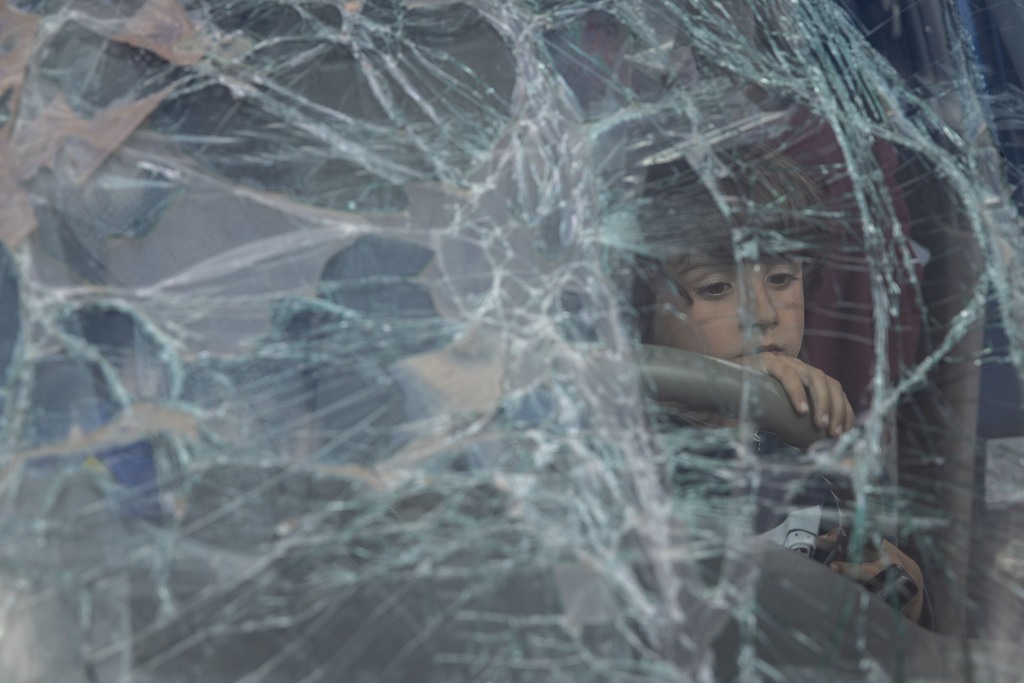 A boy from Mariupol looks through the smashed windshield of his family's car