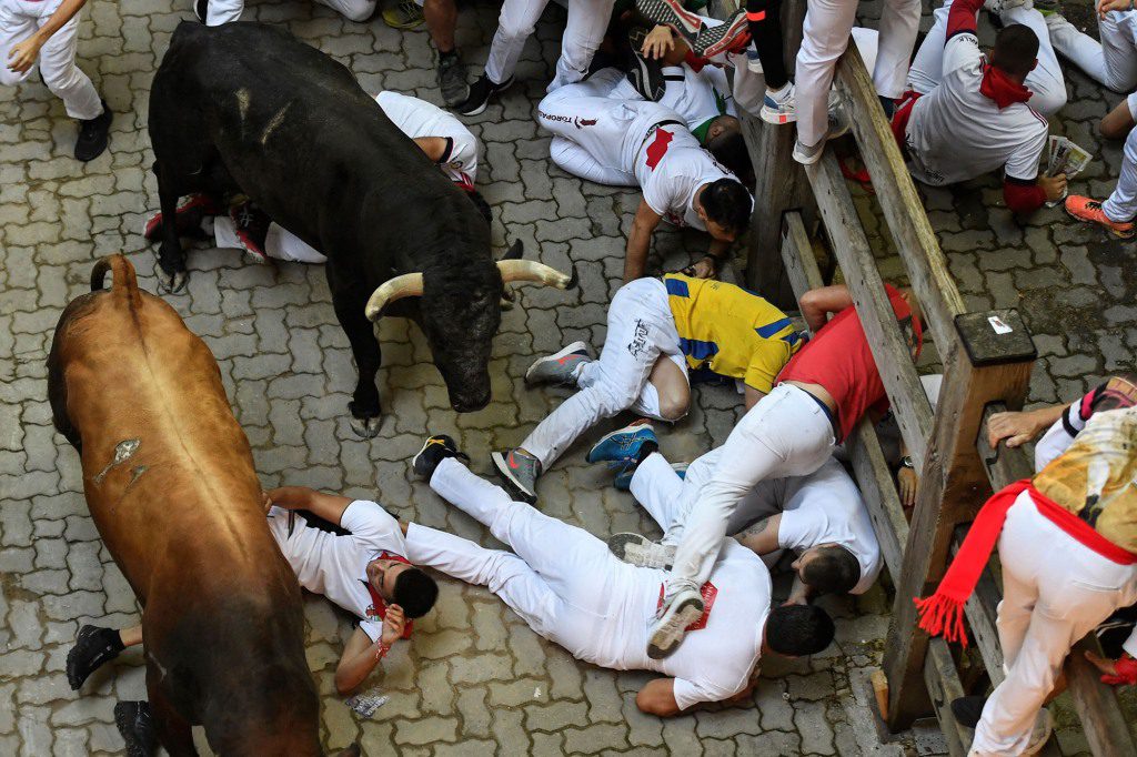 Reckless runners appear injured in the street during the last bloody bull run.